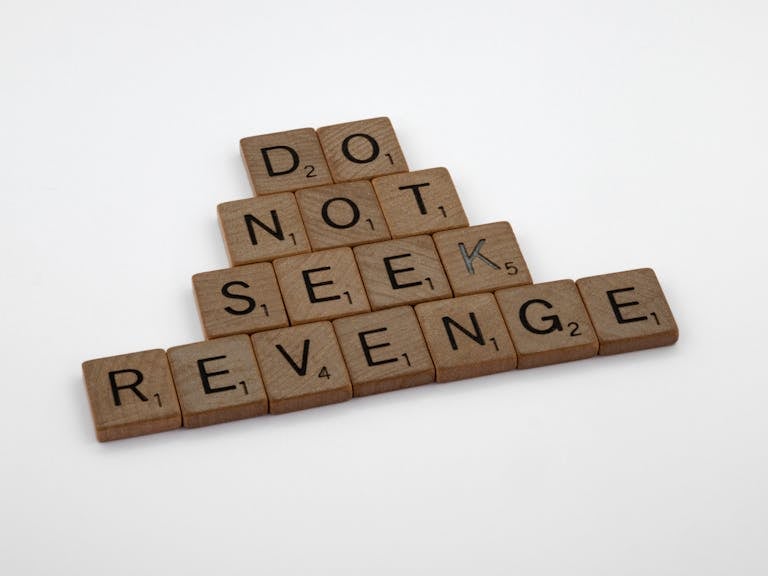 Wooden tiles arranged to spell an inspiring message about avoiding revenge.