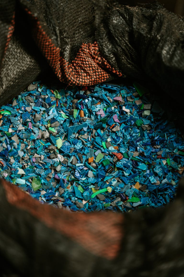Detailed close-up of colorful recycled plastic fragments in a black sack, showcasing sustainability.